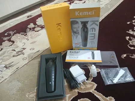 ماشین اصلاح موی صورت کیمی مدل KM-2299+5Vadapter، اصلاح به صورت خط زن، منبع انرژی باتری قابل شارژ، تکنولوژی اصلاح به صورت برش مستقیم، مدت زمان شارژ 180 دقیقه و مدت زمان استفاده پس از شارژ 180 دقیقه، به همراه آداپتور، برس تمیزکننده، روغن، 3 عدد شانه